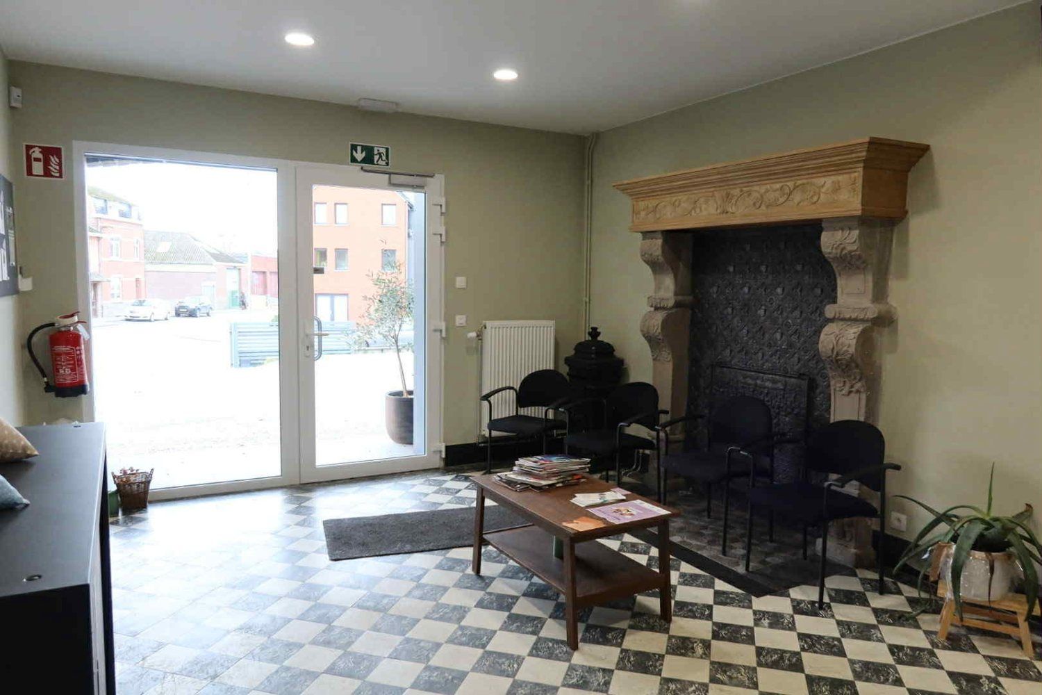 La salle d'attente, avec sa cheminée ancienne et son carrelage en damier